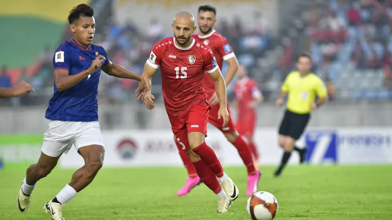 Cầu thủ Myanmar dẫn bóng qua cầu thủ Syria trong trận đấu bóng đá Cầu thủ Myanmar dẫn bóng qua cầu thủ Syria trong trận đấu bóng đá